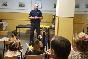 Policjant rozmawia z cudzoziemcami oraz rozdaje  elementy odblaskowe