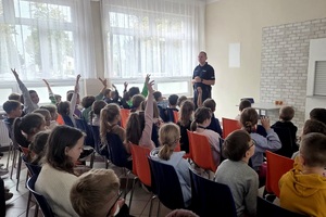 Policjant rozmawia z uczniami o bezpieczeństwie na drodze