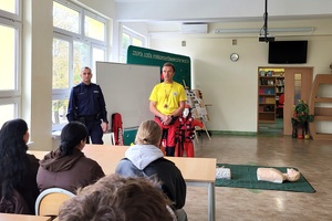 Policjant i ratownik WOPR rozmawiają z uczniami na temat udzielania pierwszej pomocy przedmedycznej