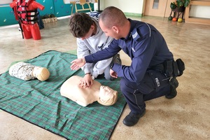 Policjant i ratownik WOPR rozmawiają z uczniami na temat udzielania pierwszej pomocy przedmedycznej